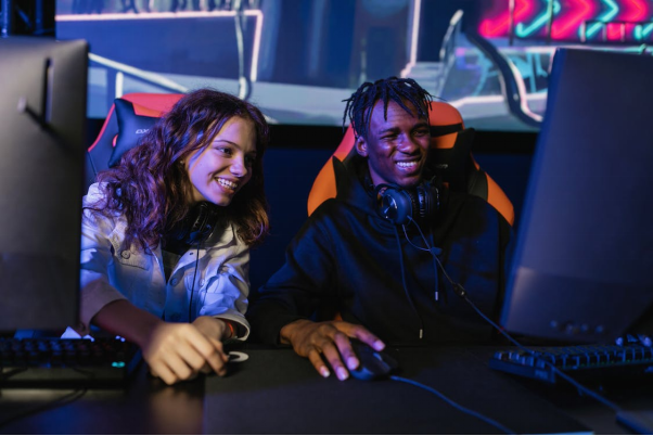 Two people are smiling while looking at a PC screen